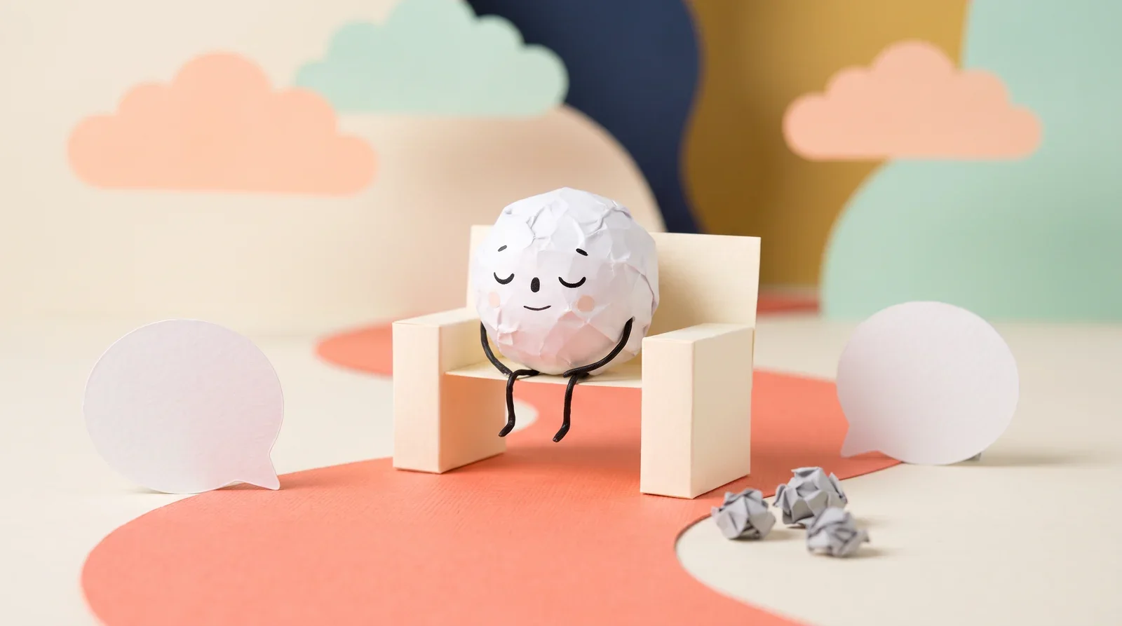 Pip the paper ball resting with eyes closed on a cream bench shaped like a pause symbol, beside a coral paper path and empty speech bubbles